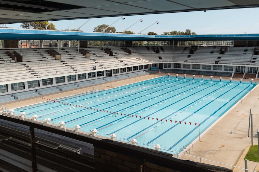 A picture of a still Olympic sized swimming pool taken from a grandstand