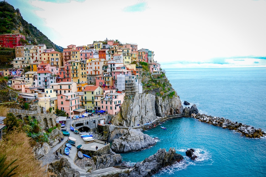 A colourful town on the edge of a cliff next to the ocean.