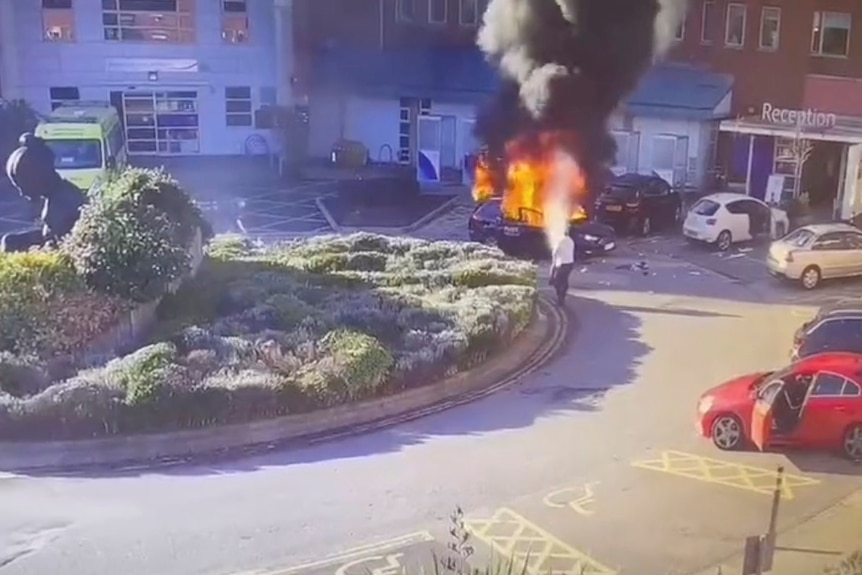 A man extinguishing a burning taxi following an explosion