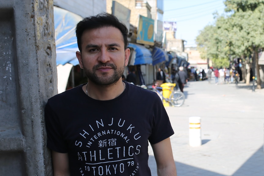 A young Hazara man in a black Tshirt standing in a street