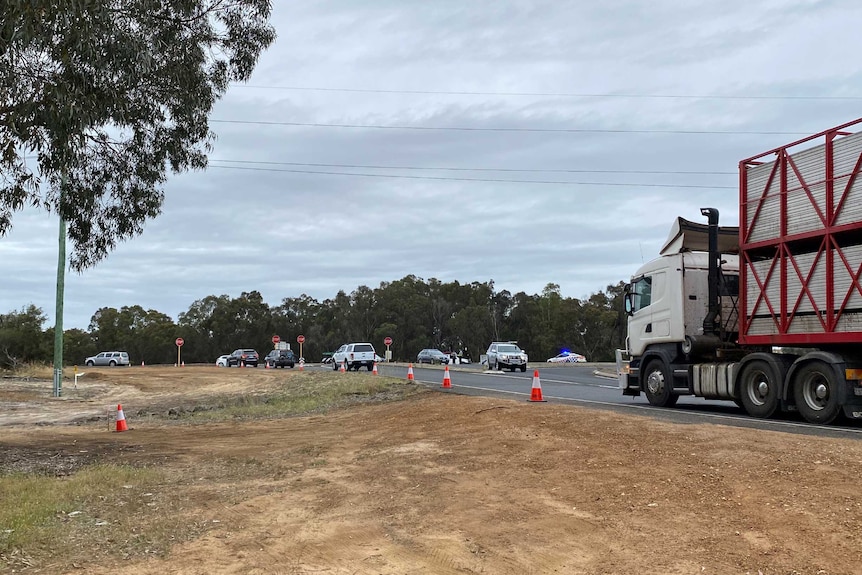 A road block on a highway with police cars and flashing lights.