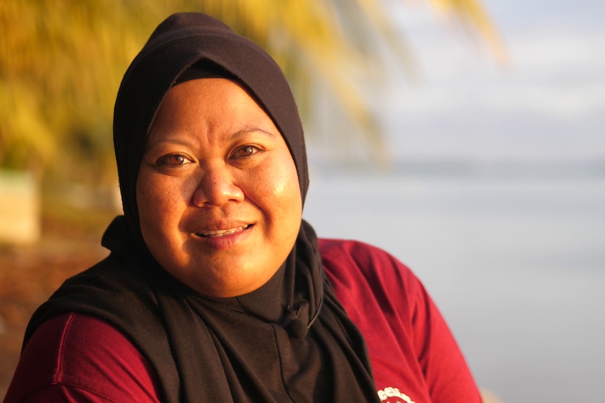 Home Island resident Seriwati Iku sits by the water at sunset. 