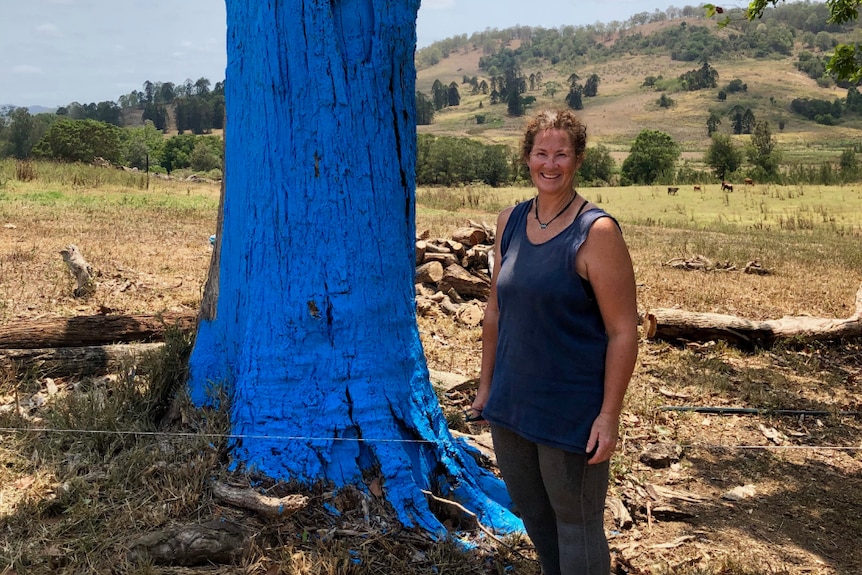 Libby Rough standing in front of a blue tree.