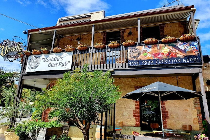 A sandstone two storey pub under blue skies.