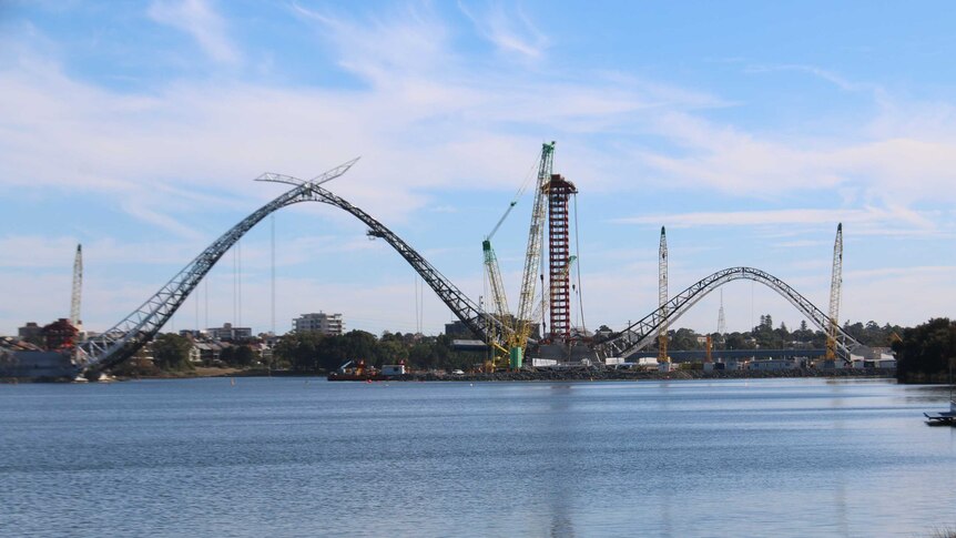 A wide, long-distance shot of the Perth Stadium footbridge under construction across the Swan River.