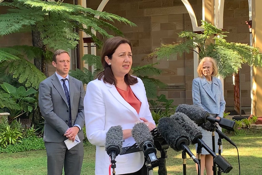 Steven Miles and Jeannette Young stand in the background as Annastacia Palaszczuk speaks to the media.