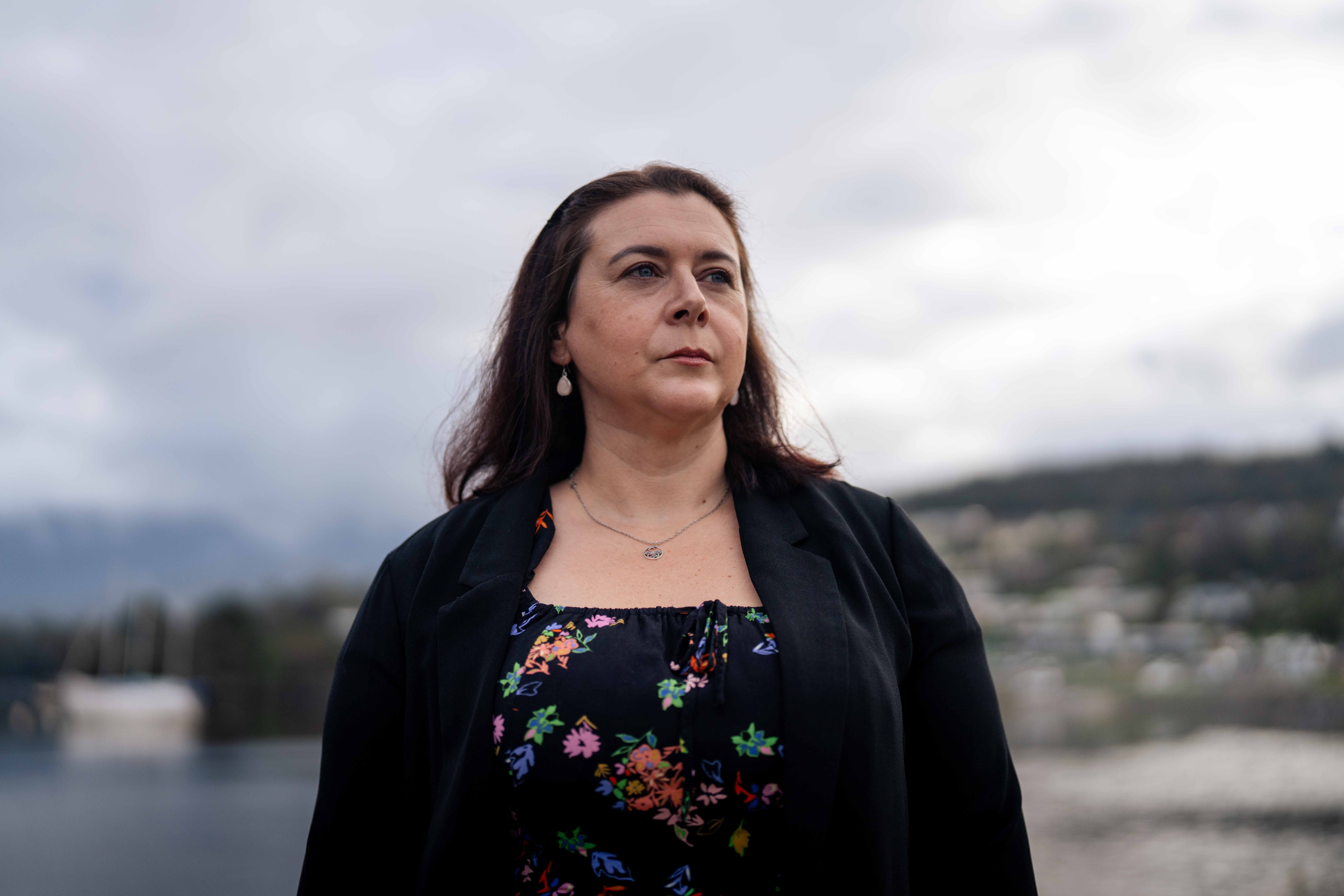 Woman sits on a park bench on a cloudy day, serious expression