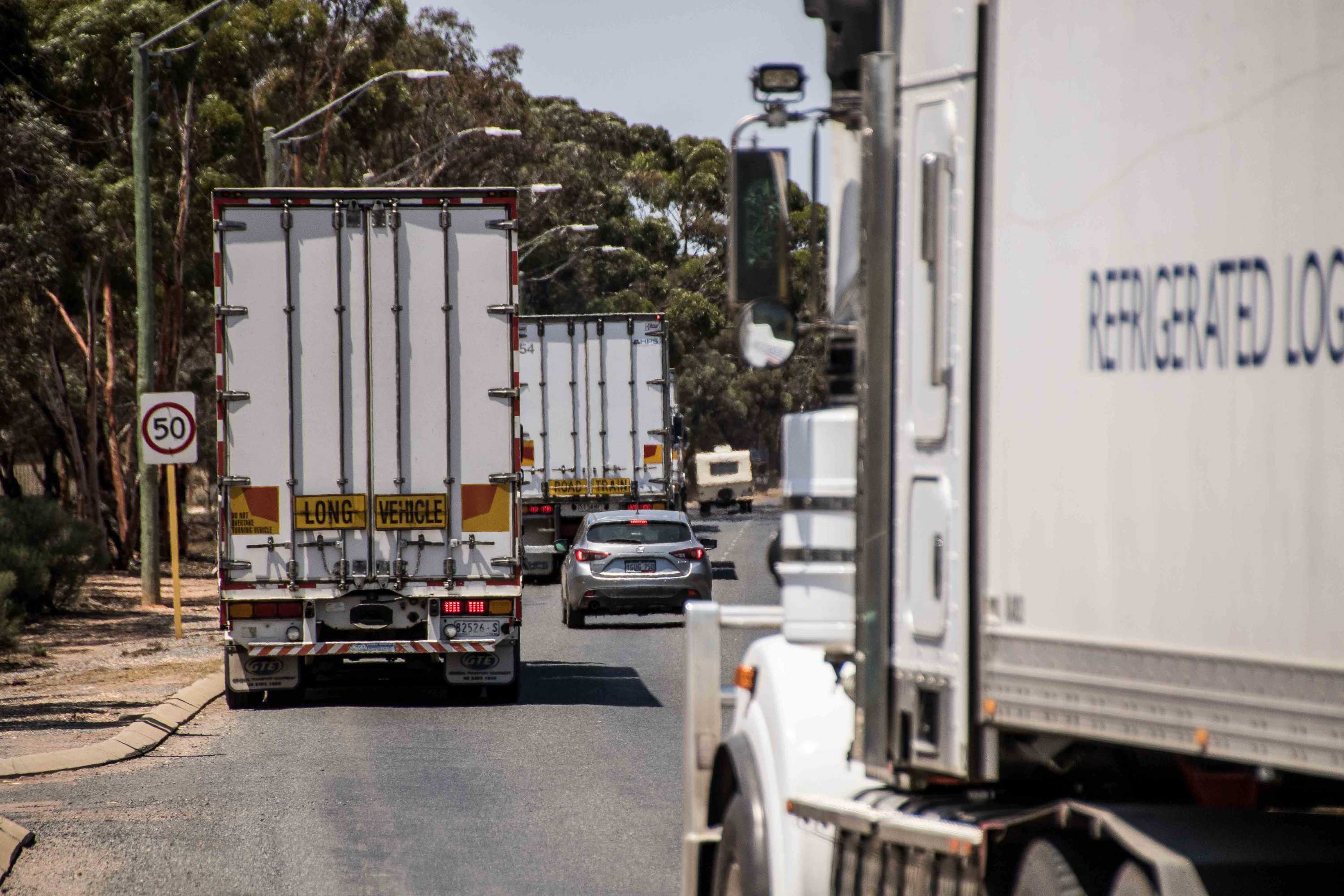 Trucks and cars driving along a country road.