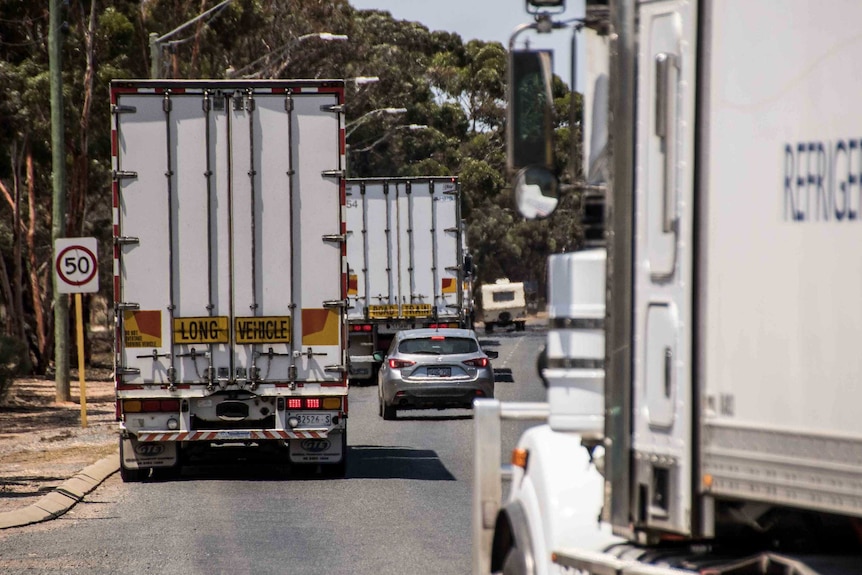 Trucks and cars driving along a country road.