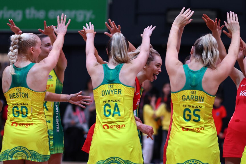 Australian netballers form two lines and join their hands above their heads as an English player runs between them.