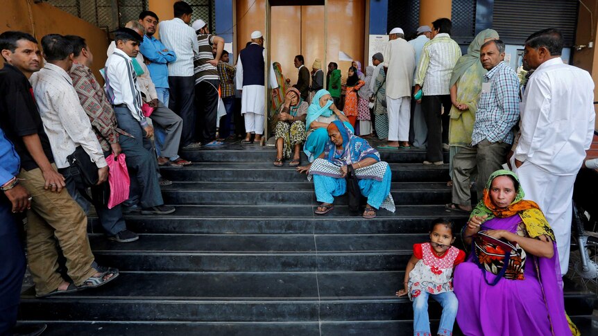 People queue outside a bank in India.