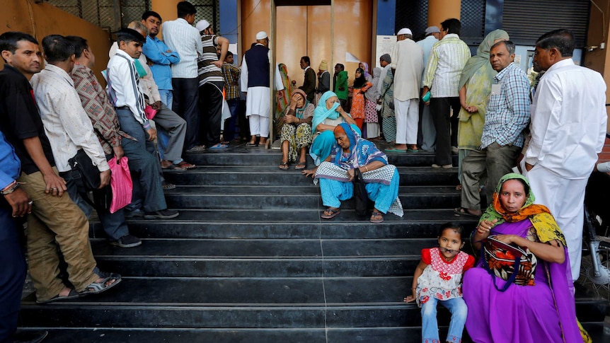 People queue outside a bank in India.