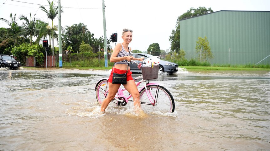 A woman walks her bike through a flooded street on March 01, 2022 in Tweed Heads, Australia.