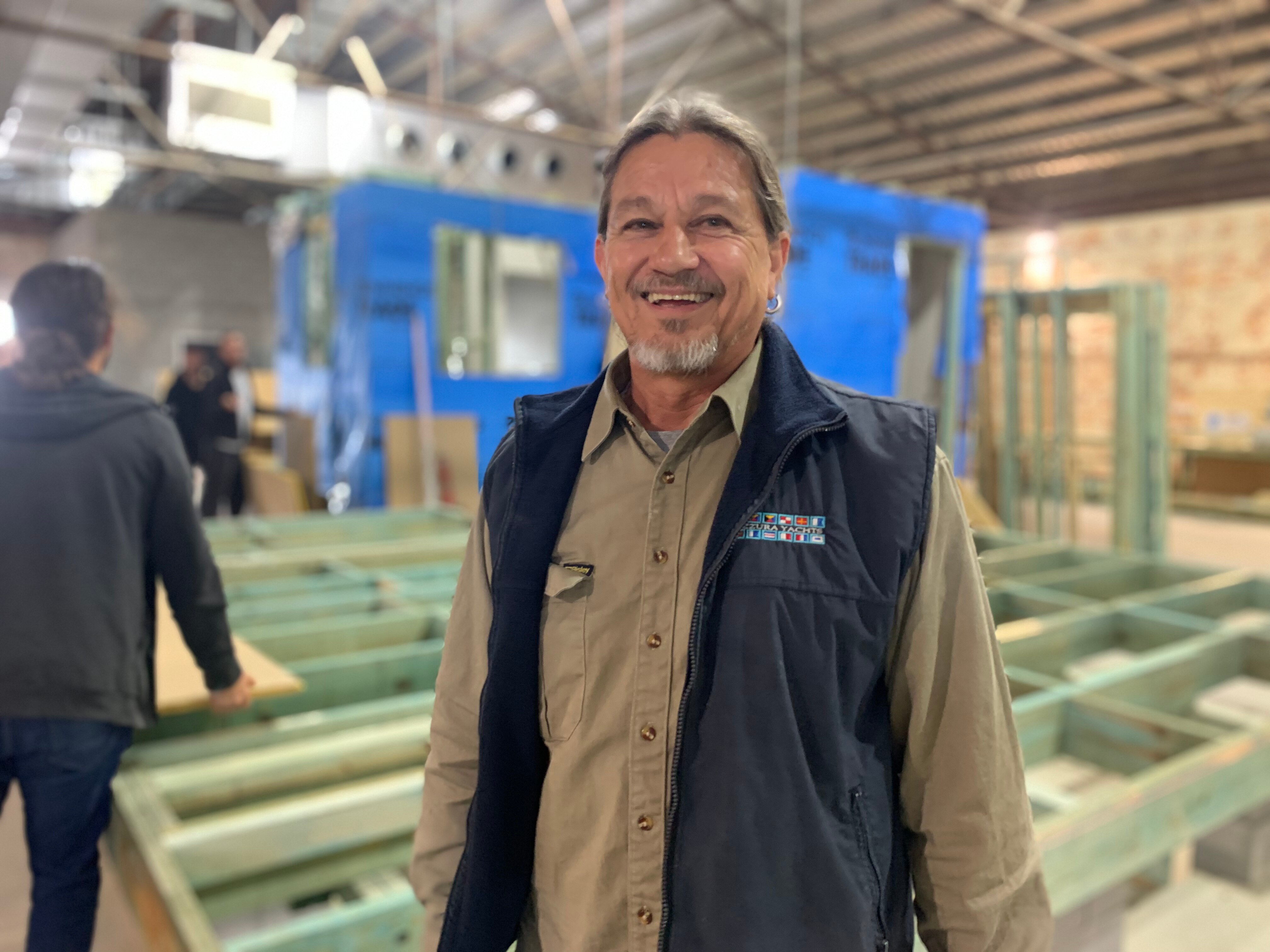 Carpentry trainer smiling in front of timber building shell