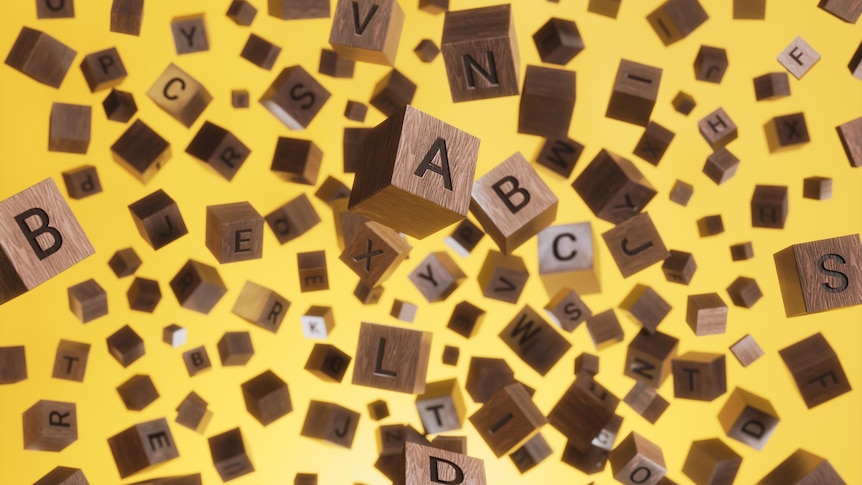 Scattered small wooden letter blocks on a yellow background