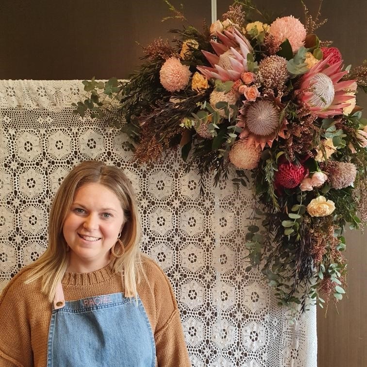 A woman standing in front of a wall with flowers.