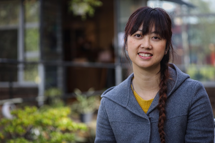 A woman with long black hair in a plait smiles