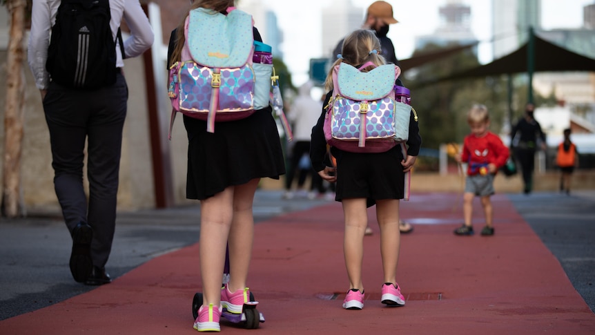 Children walking to their classrooms with schoolbags on.