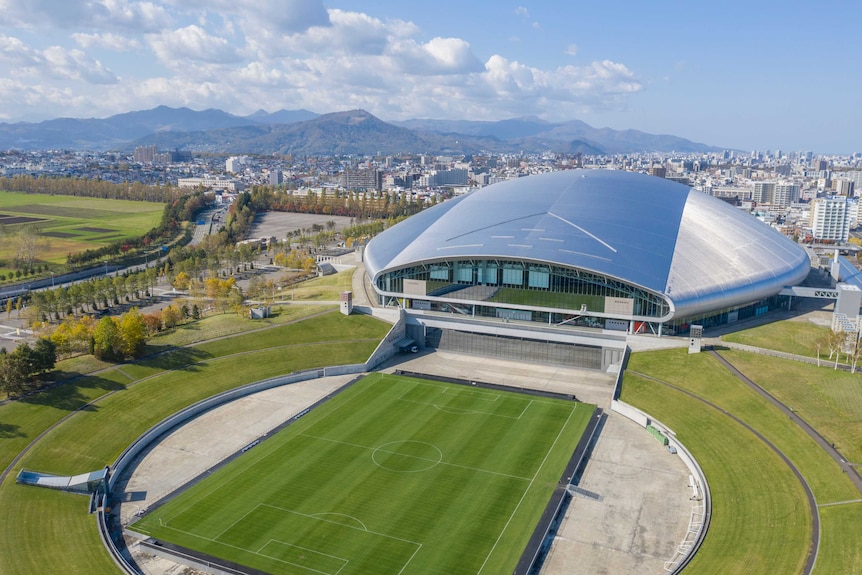 An aerial view of Sapporo Dome and the green pitch in front of it.
