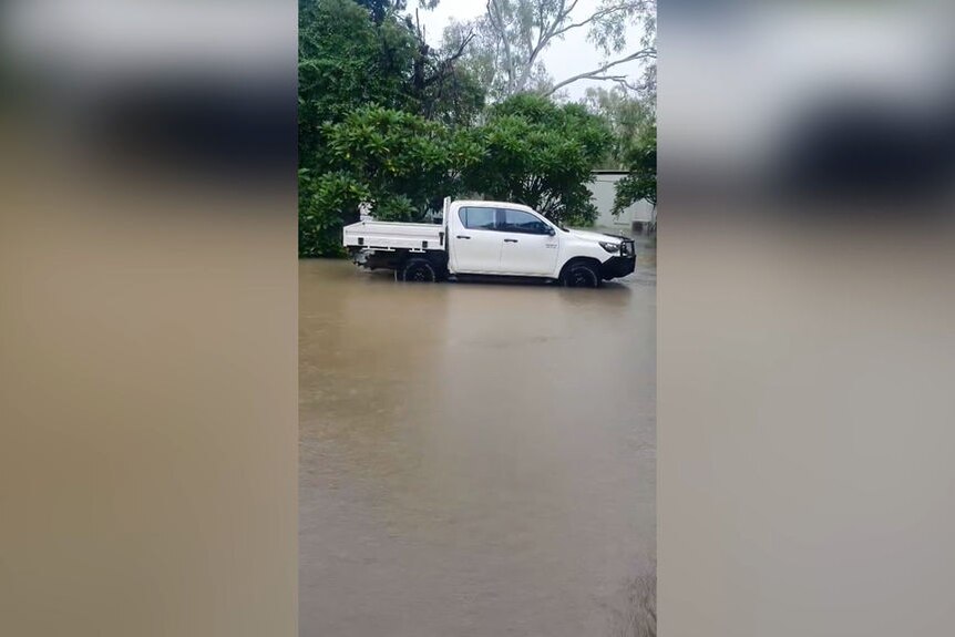 Mobile phone vision shows a ute on a flooded street.