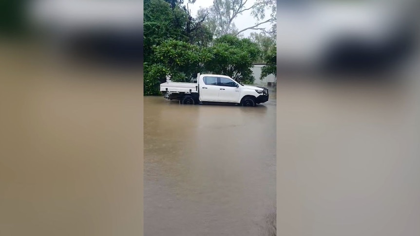 Mobile phone vision shows a ute on a flooded street.