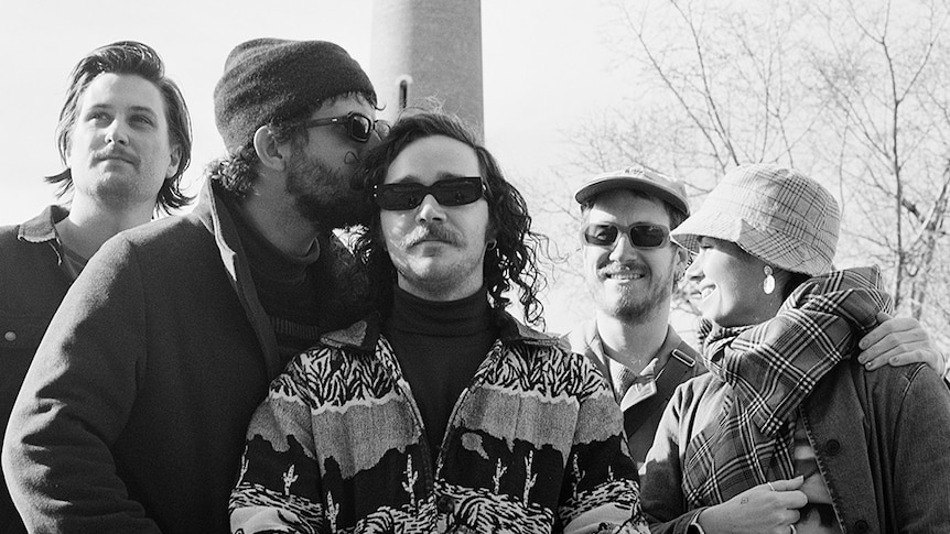 A black and white photo of five musicians, three wearing shades