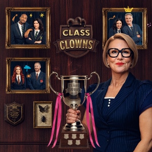 A lady with bold specs holding Class Clowns Cup with photograph images behind of comedians
