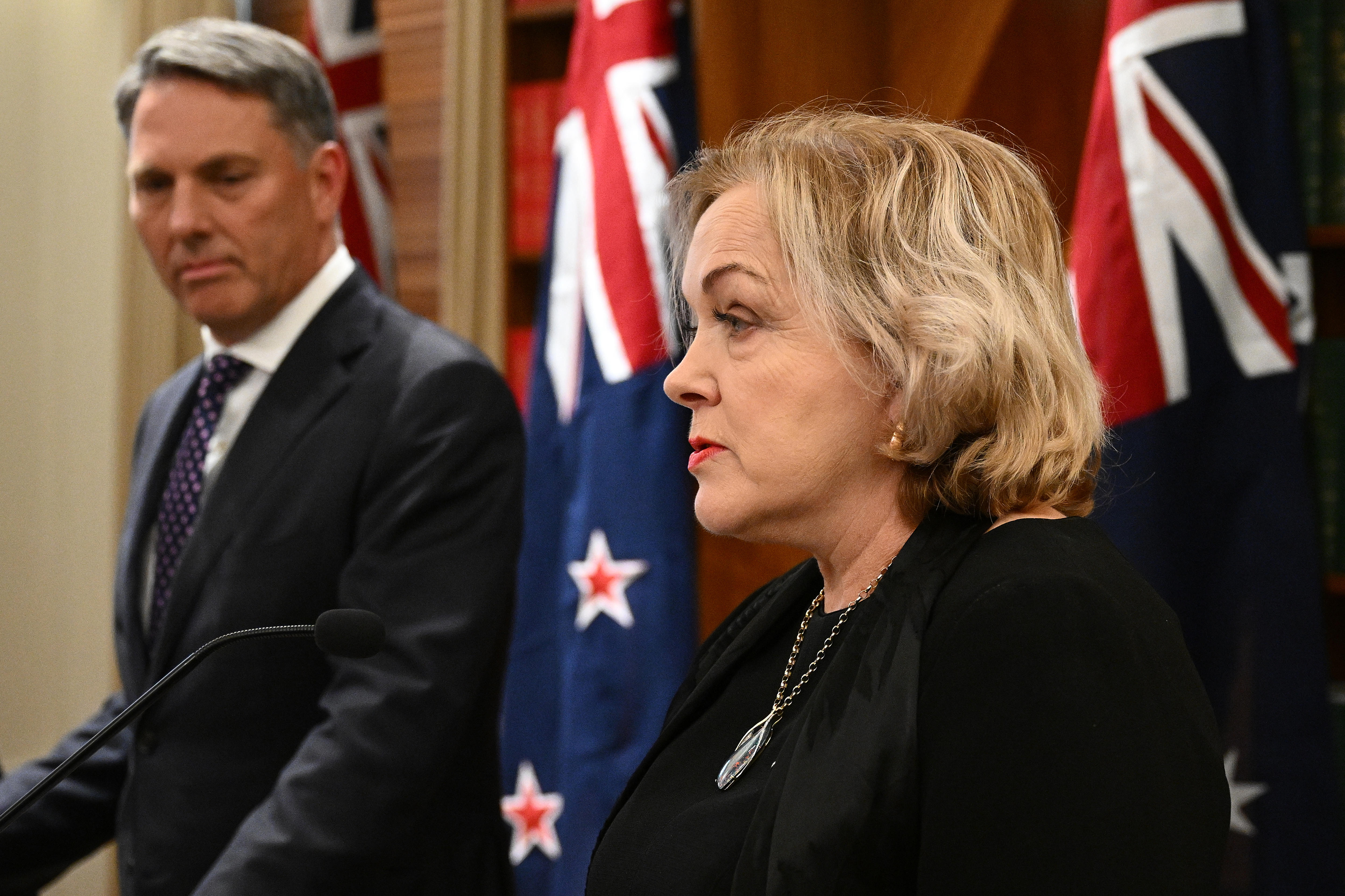 Collins and Richard Marles stand side by side with Australian and NZ flags behind them.