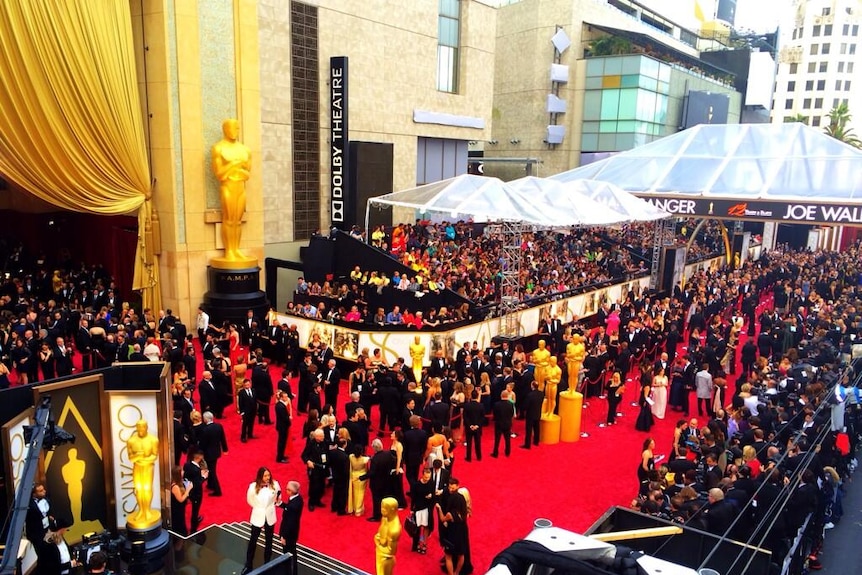 Celebrities line up to enter Dolby Theatre ahead of The Oscars, with crowds of people in two lines on a red carpet.