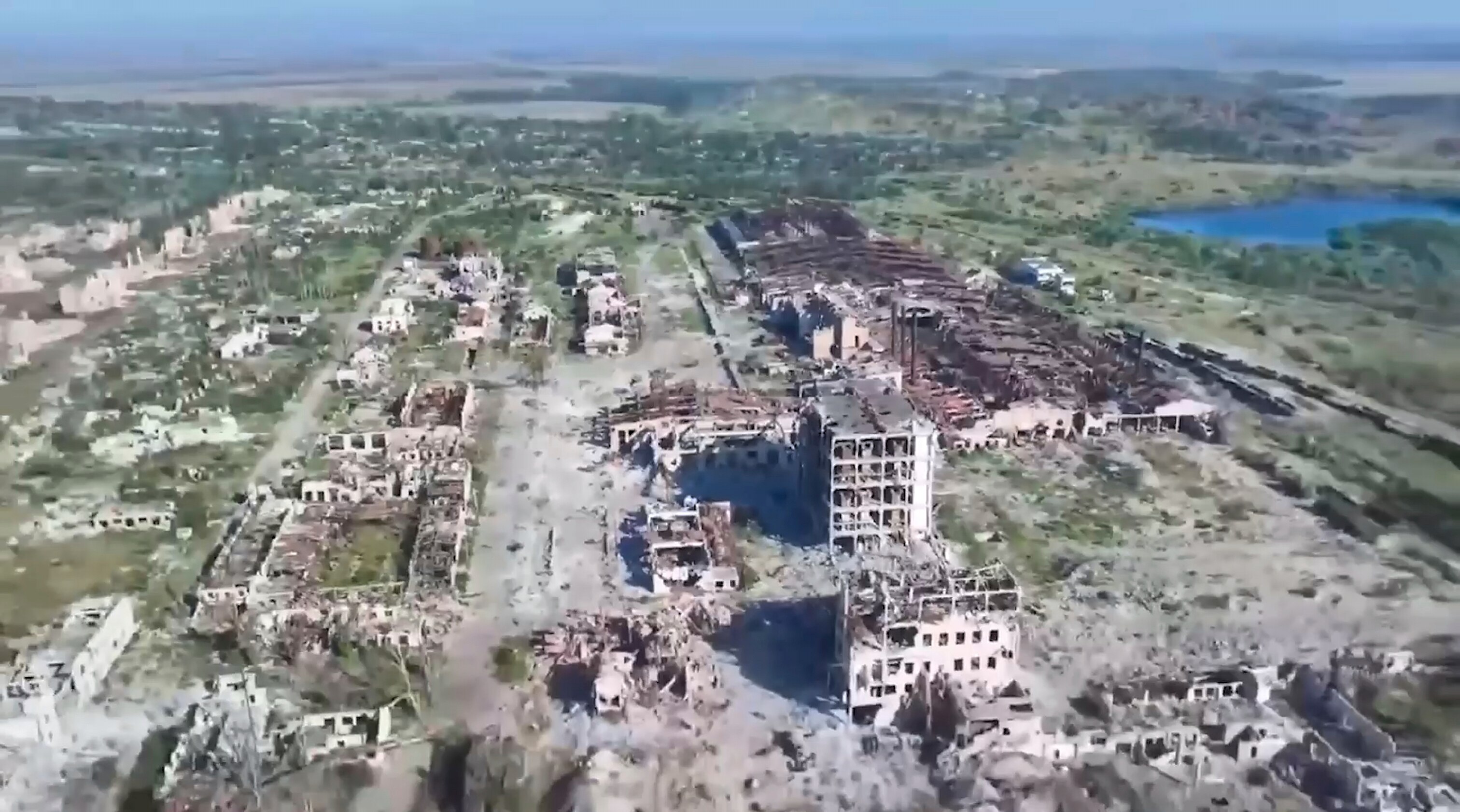 The town of Chasiv Yar seen from above, with various destroyed buildings and patches of dirt surrounded by greenery