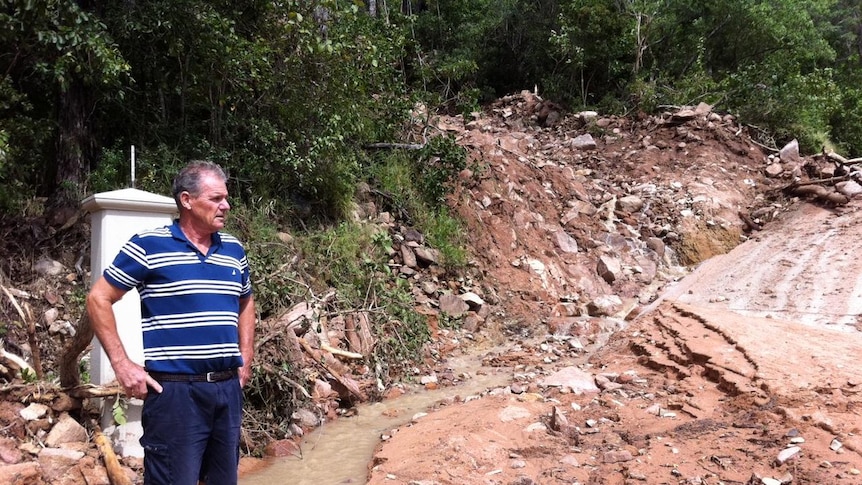 A resident looks at a mudslide in his driveway at Hideaway Bay.