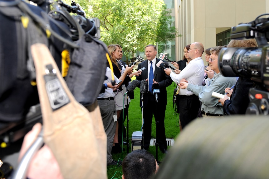 Anthony Albanese speaks surrounded by cameras and reporters. 