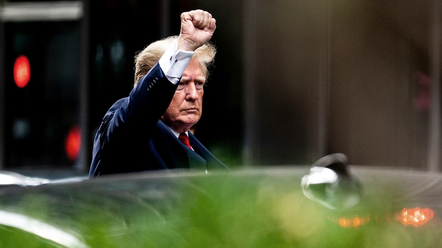 Donald Trump raises his fist as he leaves Trump Tower