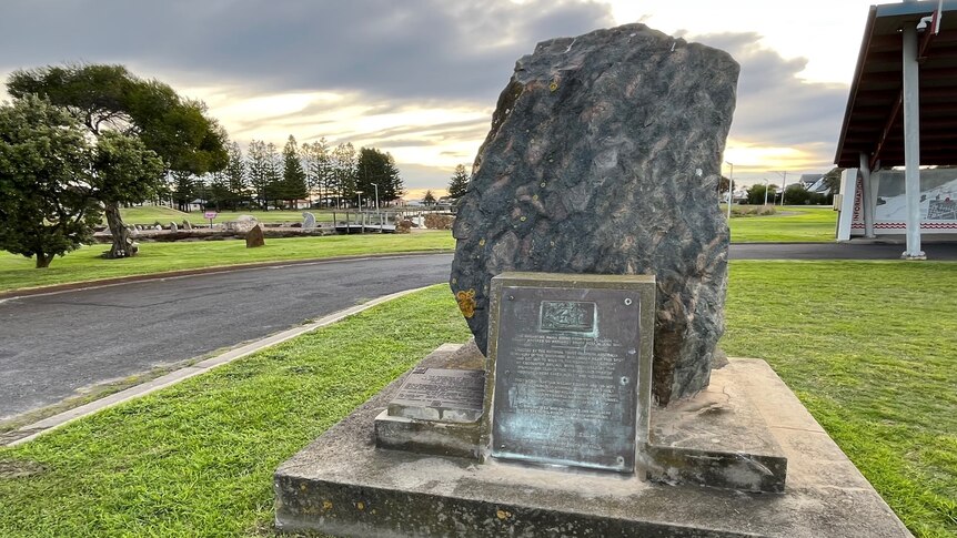 A large rock with a plaque in a park