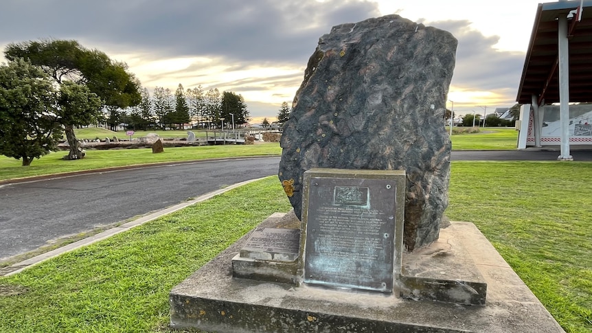 A large rock with a plaque in a park
