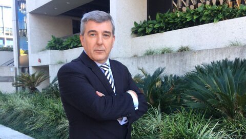 RACQ spokesman Paul Turner stands in front of Brisbane building with arms crossed
