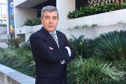 RACQ spokesman Paul Turner stands in front of Brisbane building with arms crossed