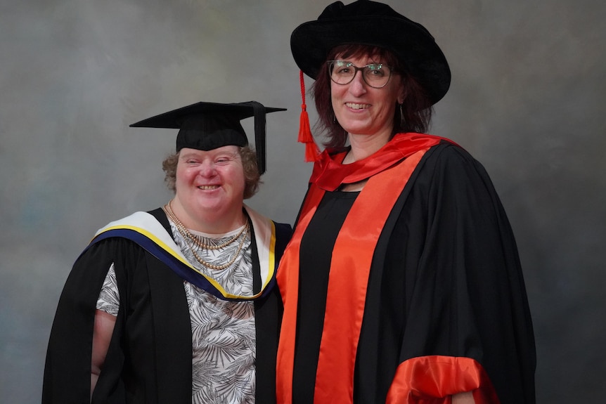 Two women wearing academic gowns and hats