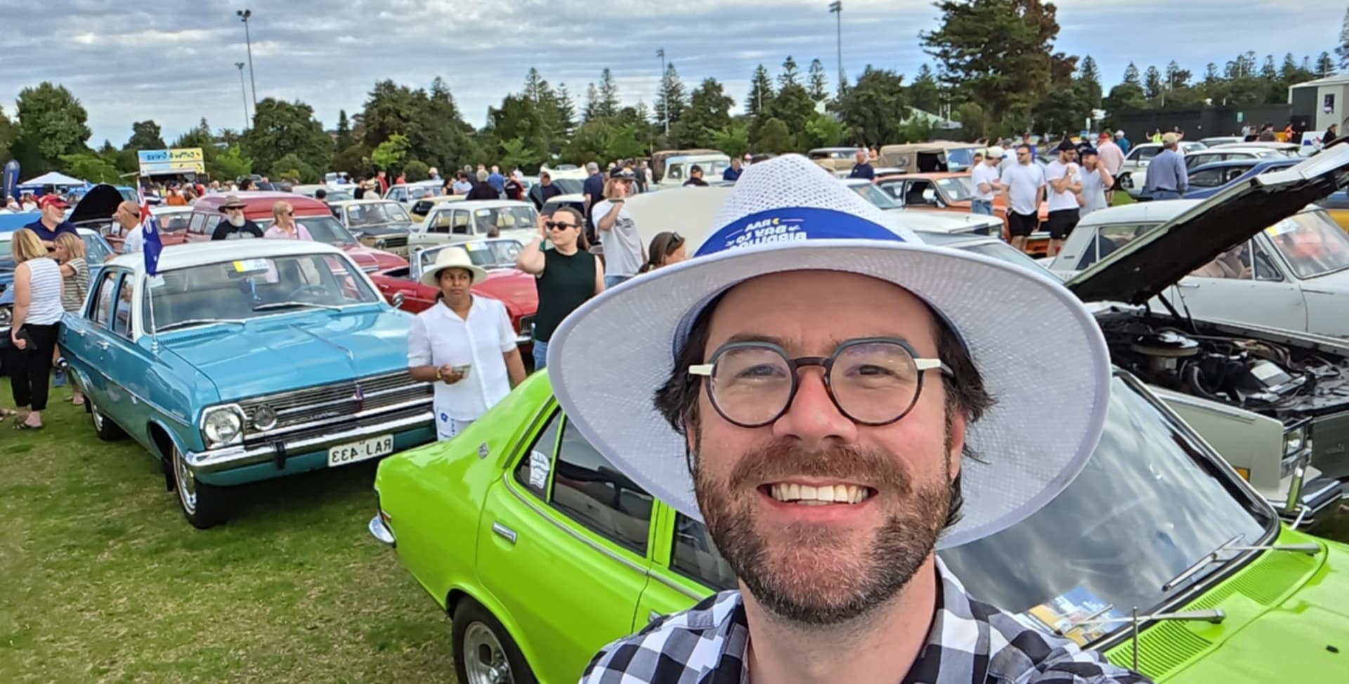 A man stands in front of rows of historic cars.