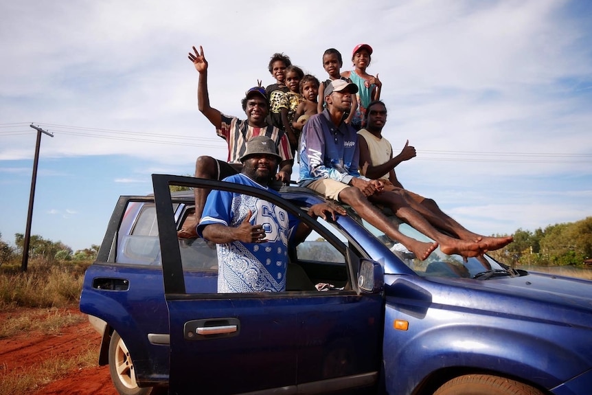 A group of men sit on a car during a football match in Bidyadanga in June 2022. 