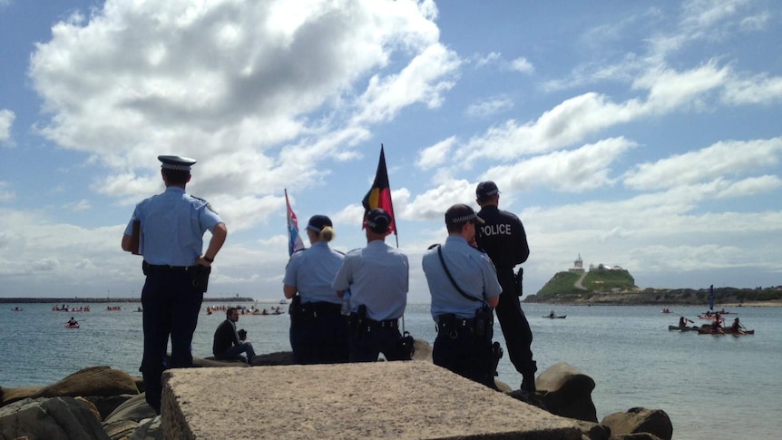 Police watch protesters on Newcastle Harbour.
