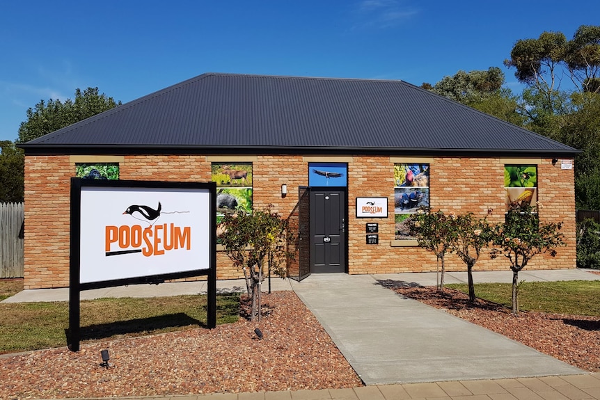 A single-storey brick building with a sign saying "Pooseum" out the front