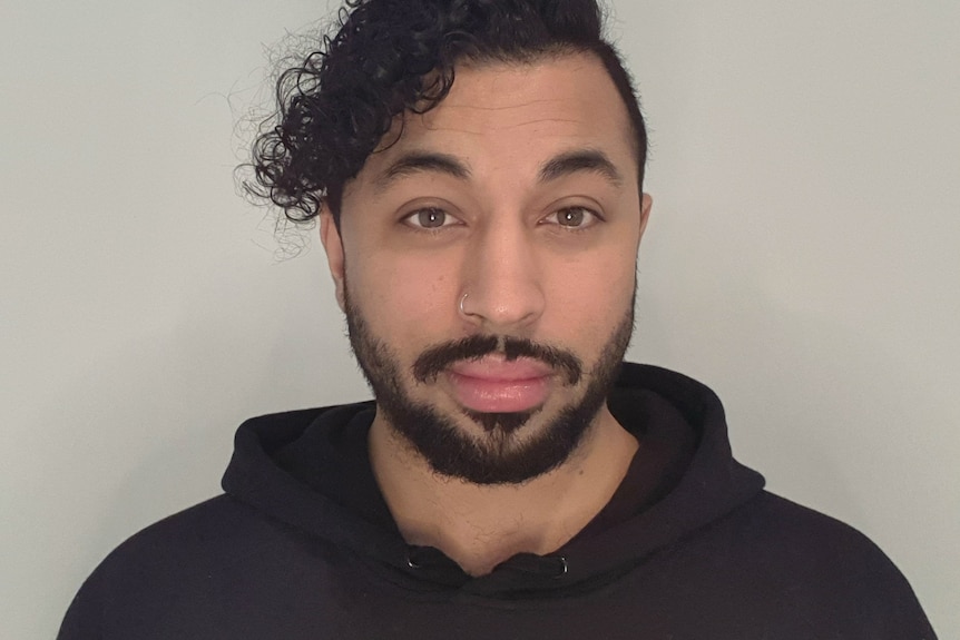 Profile image of a man in a black hoodie smiling to camera.