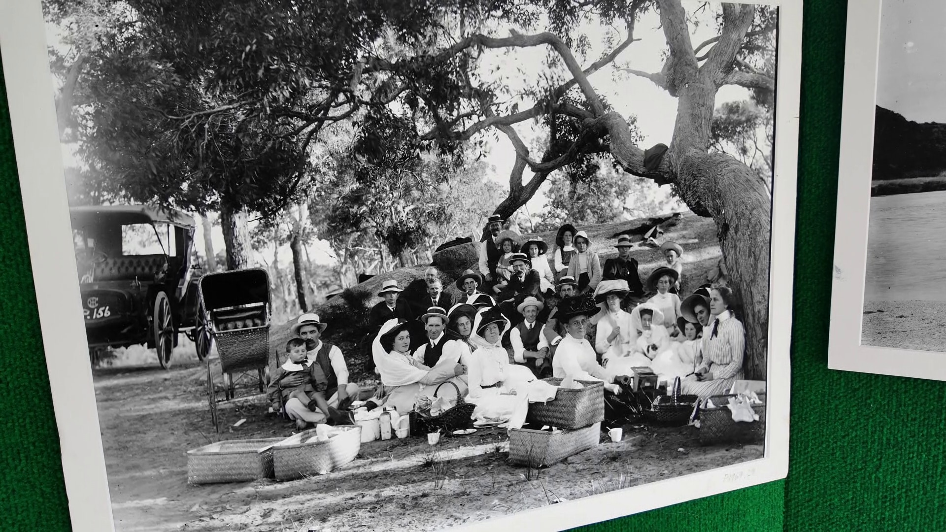 A black-and-white photograph of people having a picnic in early 1900s dress