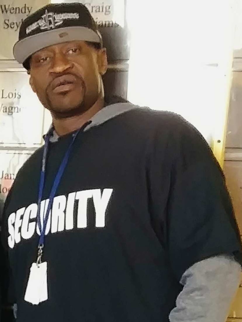 An African American man in a cap and a t-shirt with security written across it