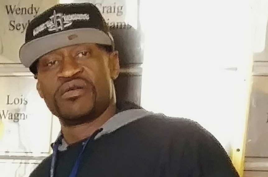 An African American man in a cap and a t-shirt with security written across it