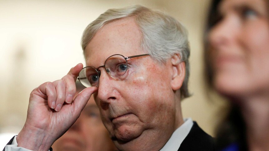 Senate Majority Leader Mitch McConnell adjusts his glasses.