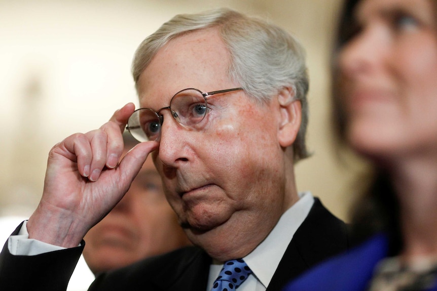 Senate Majority Leader Mitch McConnell adjusts his glasses.