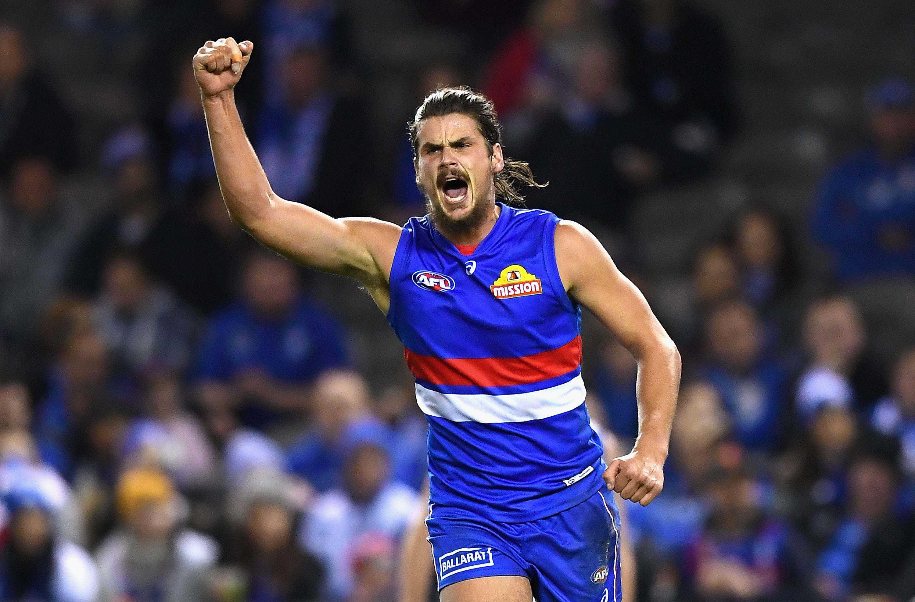 Tom Boyd raises a fist and shouts to celebrate during an AFL game.