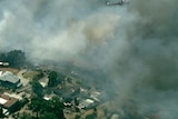 An aerial shot of fire burning and blowing smoke over homes
